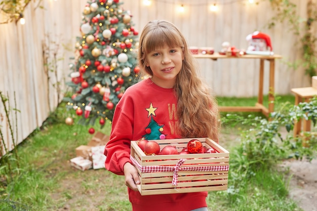 Noël en famille en juillet Portrait de jeune fille près de l'arbre de Noël avec des cadeaux