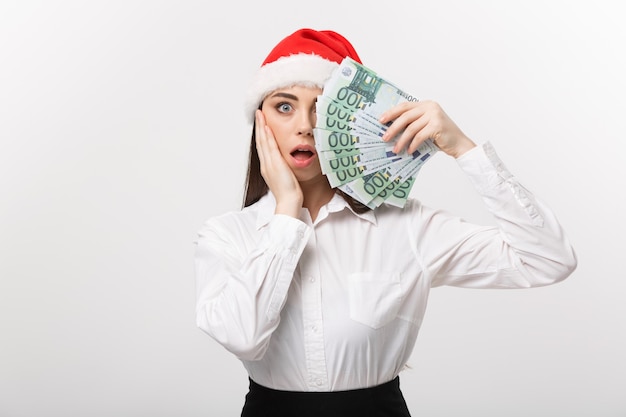 Noël et finance concept jeune femme d'affaires montrant de l'argent fermant son visage avec une expression de surprise