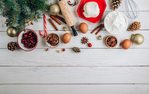 Noël - fond de gâteau de cuisson. Ingrédients de la pâte et décorations sur table en bois blanc