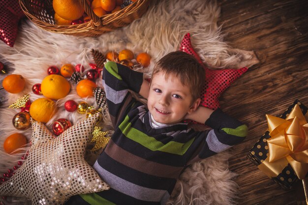 Noël garçon couché sur sa peau autour de jouets de mandarine ornements pour arbre de Noël