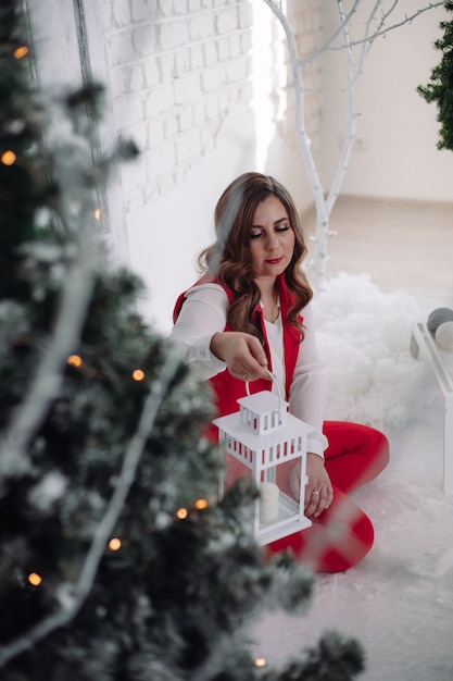 Noël. Jeune fille. Se réconcilier. Coiffure saine. Dame élégante à côté de l'arbre de Noël Bonne année.