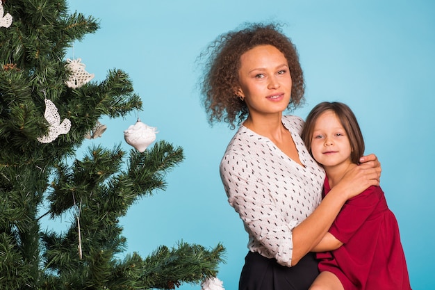 Noël de la jeune maman et sa fille avec arbre de Noël sur bleu