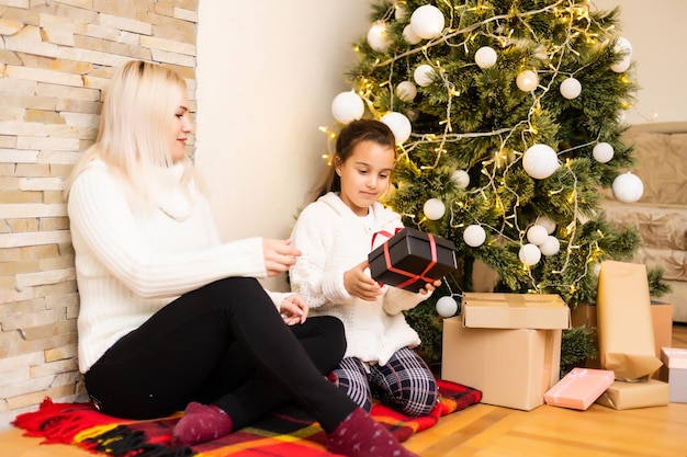 Noël, mère de famille heureuse avec sa fille avec des cadeaux la veille de Noël