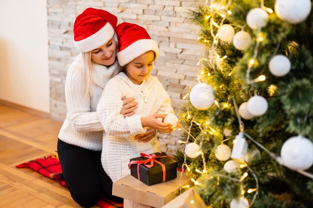 Noël, mère de famille heureuse avec sa fille avec des cadeaux la veille de Noël