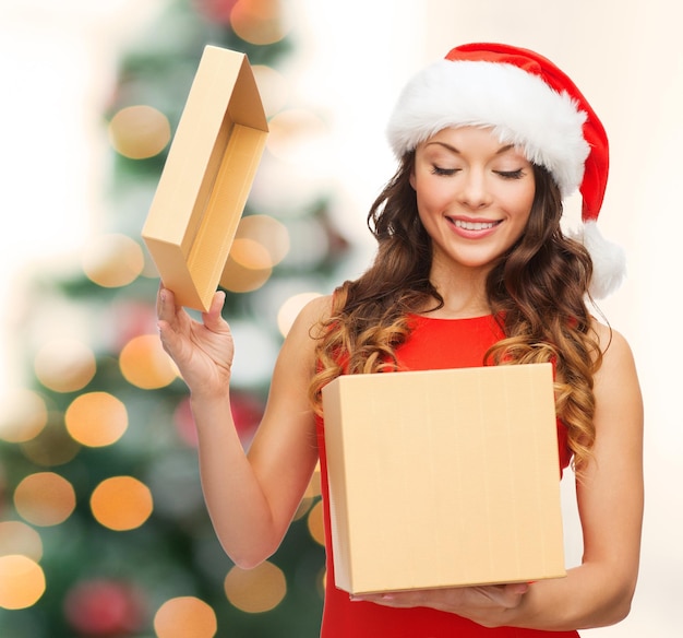 Noël, Noël, hiver, concept de bonheur - femme souriante en bonnet de Noel avec boîte-cadeau