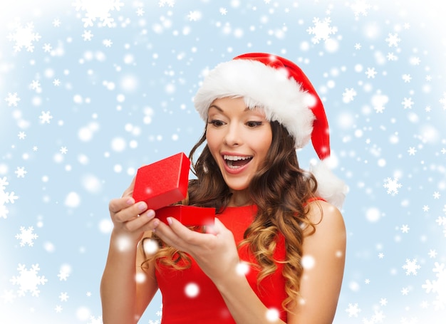 Noël, Noël, hiver, concept de bonheur - femme souriante en bonnet de Noel avec boîte-cadeau