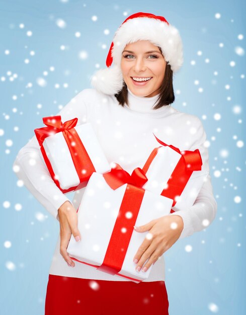 noël, noël, hiver, concept de bonheur - femme souriante en bonnet de noel avec de nombreux coffrets cadeaux