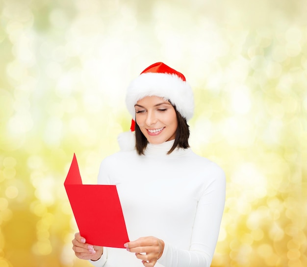 Noël, Noël, personnes, publicité, concept de vente - femme heureuse en bonnet de Noel avec carte postale rouge vierge