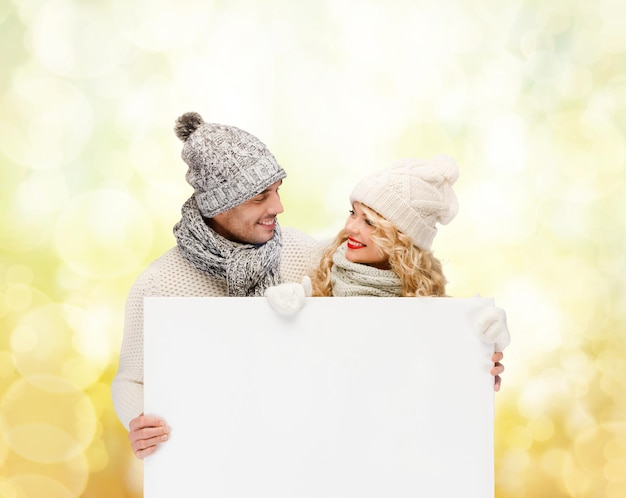 Noël, Noël, personnes, publicité, couple, concept de vente - femme et homme heureux en vêtements d'hiver avec tableau blanc vierge