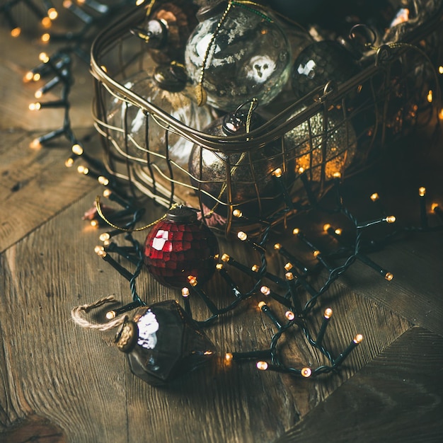 Photo noël ou nouvel an fond arbre de noël jouet décoration boules de verre dans une boîte vintage et guirlande lumineuse sur fond en bois rustique culture carrée