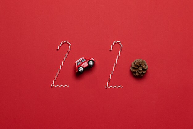 Noël et nouvel an vacances 2020 lettrage de divers jouet de voiture décoration rouge, cône de sapin sur un fond rouge