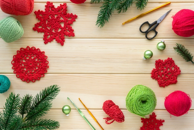 Noël à plat des articles pour la couture. Flocons de neige tricotés, fils et crochets sur fond en bois.