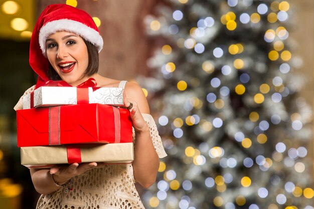 Noël Santa hat portrait de femme isolée tenir le cadeau de Noël. Sourire fille heureuse sur fond de Noël