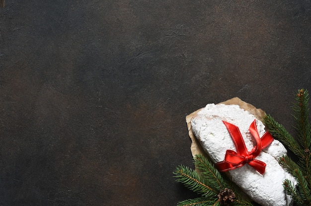 Noël stollen avec ruban rouge en cadeau sur une table en béton.