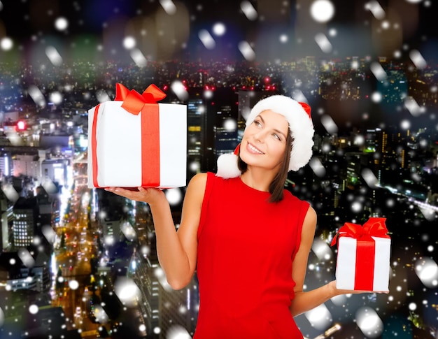 Photo noël, vacances, célébration et concept de personnes - femme souriante en robe rouge avec boîte-cadeau sur fond