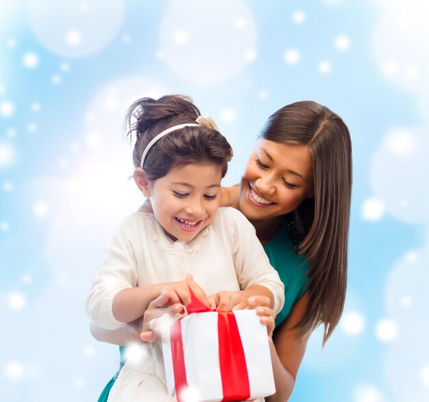 Noël, vacances, concept de famille et de personnes - heureuse mère et enfant fille avec boîte-cadeau sur fond de lumières bleues