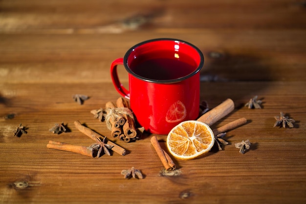 noël, vacances, cuisine et concept d'épices - gros plan d'une tasse de thé avec de la cannelle, de l'anis et de l'orange séchée sur une table en bois du haut