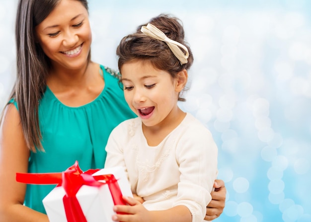 noël, vacances, fête, concept de famille et de personnes - heureuse mère et fille avec boîte-cadeau sur fond de lumières bleues
