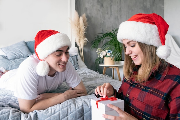 Noël, vacances, hiver, concept de personnes. Couple avec boîte cadeau cadeau portant des chapeaux de père Noël.