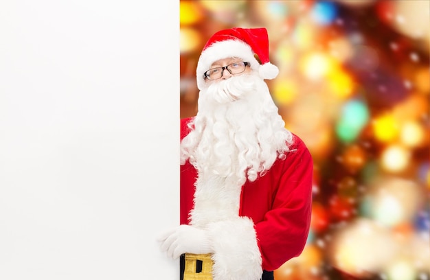 noël, vacances, publicité et concept de personnes - homme en costume de père noël avec panneau d'affichage blanc vierge sur fond de feux rouges