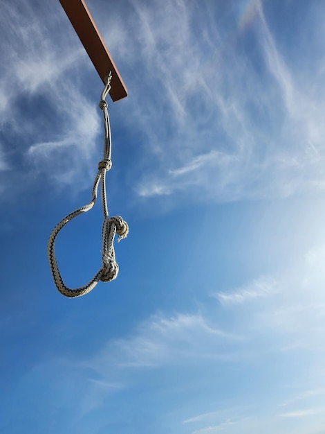 Le nœud coulant de la corde est suspendu à la potence contre le ciel bleu avec des nuages