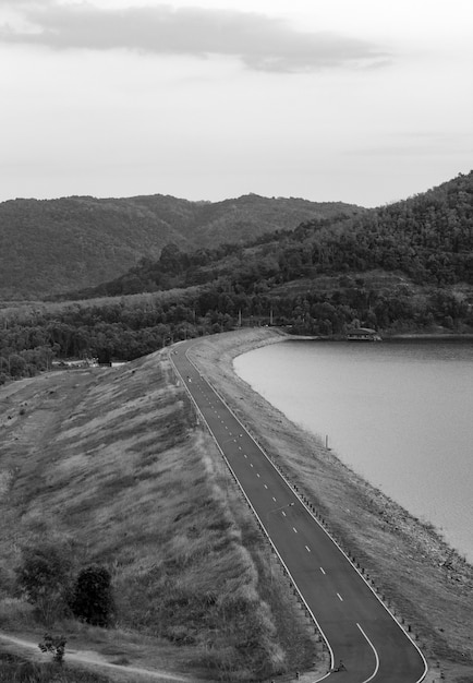 Photo noir et blanc du barrage et la route devant le barrage dans les montagnes.