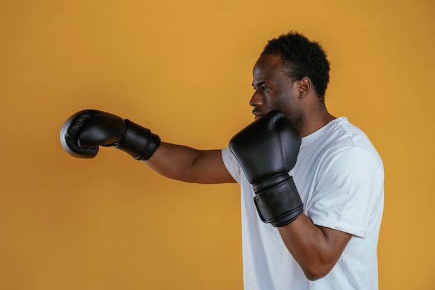 Photo le noir pratique le coup de boxe sur un fond jaune.