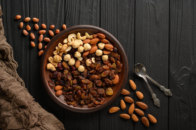 Noisettes cajous raisins secs amandes cacahuètes noix sur un fond noir en bois