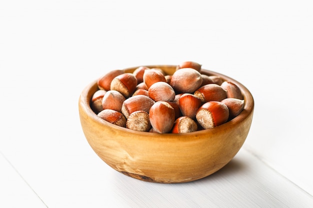 Noisettes dans un bol en bois sur une table en bois blanche. Superaliment