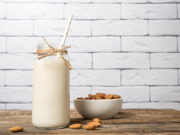 Photo noix d'amandes avec une bouteille de lait d'amande sur un fond de bois rustique