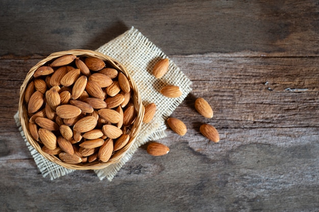 Noix d&#39;amandes dans un bol en bois sur une table en bois, vue de dessus.