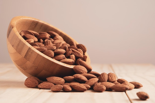 Noix d'amandes dans un bol en bois et verser sur la table avec copie espace. La noix d'amande est un aliment diététique sain riche en protéines, faible en gras et en acides aminés essentiels.