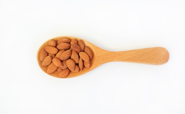 Noix d'amandes dans une cuillère en bois isolée sur fond blanc. Vue d'en-haut