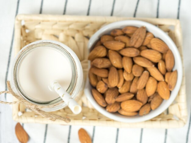 Noix amandes et lait d'amande sur une table en bois blanc