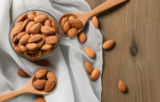 Noix d'amandes pelées dans une tasse en verre sur table en bois