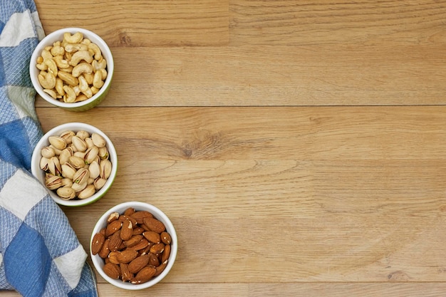 noix amandes pistaches noix de cajou dans des bols sur table en bois