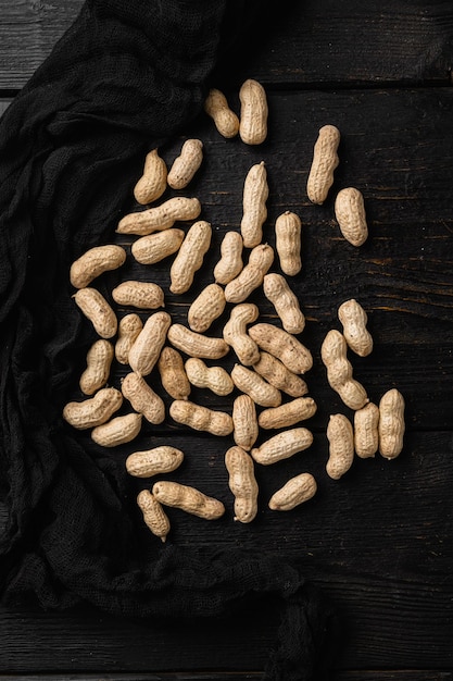 Noix d'arachide entières sur fond de table en bois noir vue de dessus mise à plat