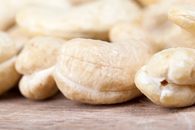 Noix de cajou crues délicieuses et saines, gros plan de noix de cajou pelées sur la table de la cuisine, noix de cajou croquantes