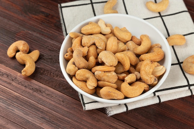 Noix de cajou dans un bol blanc sur la table, collation saine, nourriture végétarienne.