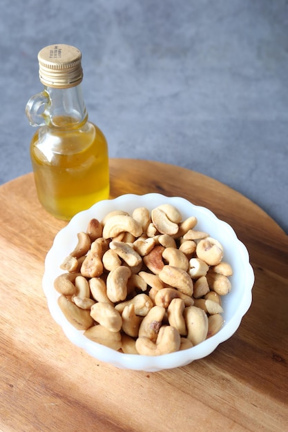 Noix de cajou dans un bol et un pot d'huile sur une table en bois