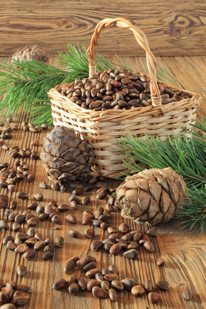 Noix de cèdre et cônes de cèdre dans un panier en osier sur une table en bois