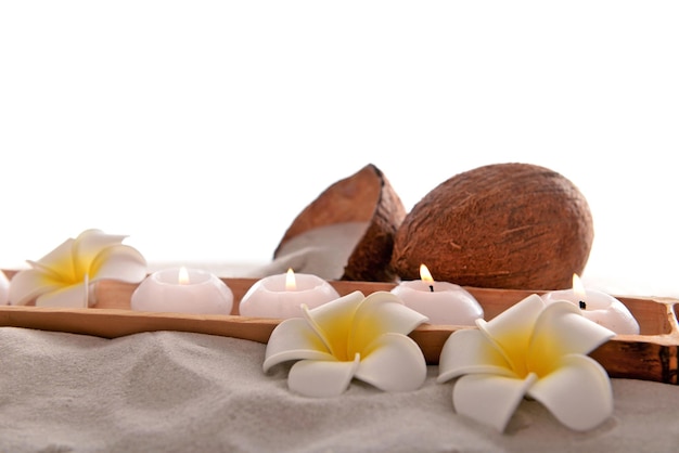 Noix de coco avec bougies et plumeria sur sable isolé sur blanc