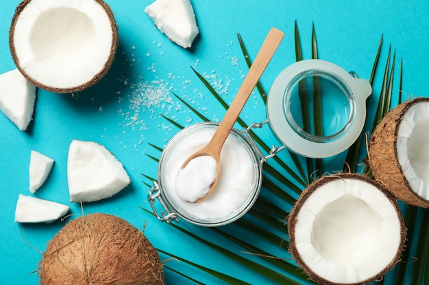 Noix de coco, branche de palmier et cosmétique sur turquoise. Fruit exotique