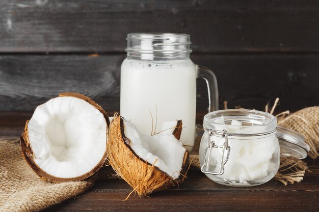 Noix de coco cassée et lait de coco sur bois noir