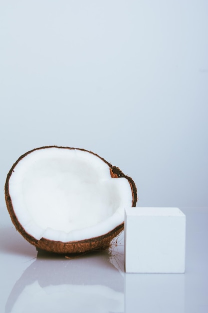 Noix de coco coupée en deux sur fond blanc avec réflexion et accessoires pour le produit