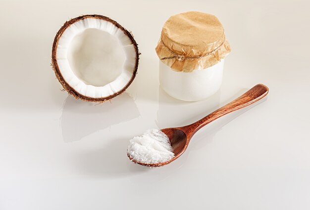 Noix de coco, cuillère en bois et pot de beurre de coco