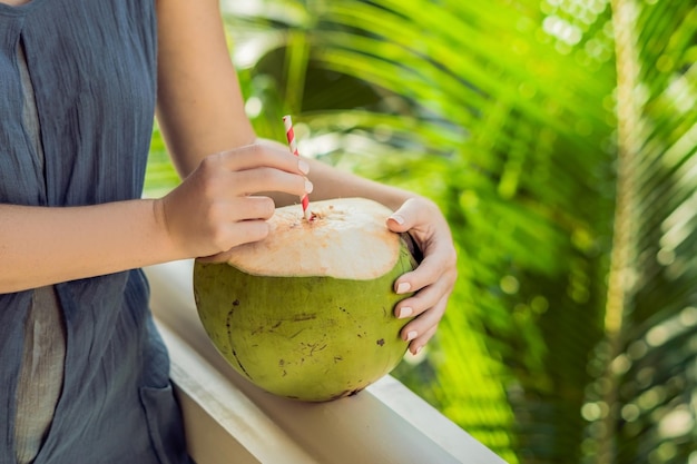 Noix de coco dans de belles mains féminines sur fond vert. Les avantages du concept d'eau de noix de coco.