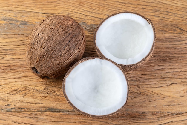 Noix de coco et demi-fruits fêlés sur table en bois