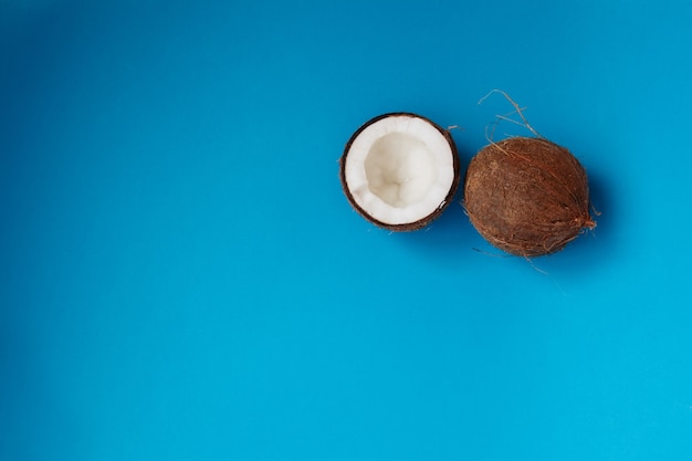 Noix de coco entière et coupée en deux sur fond bleu