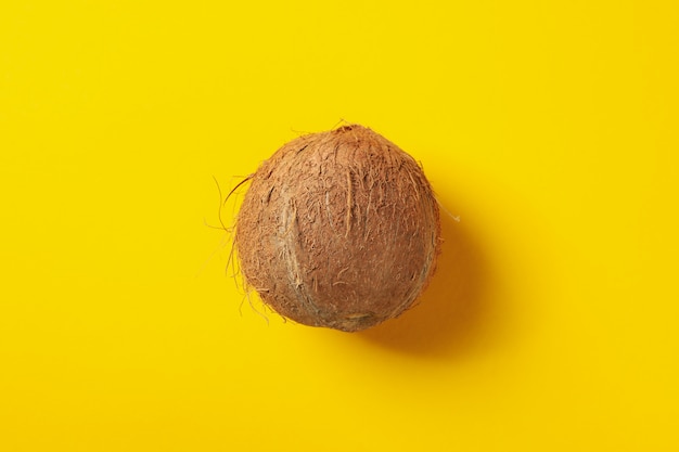 Noix de coco entière sur table jaune, vue de dessus